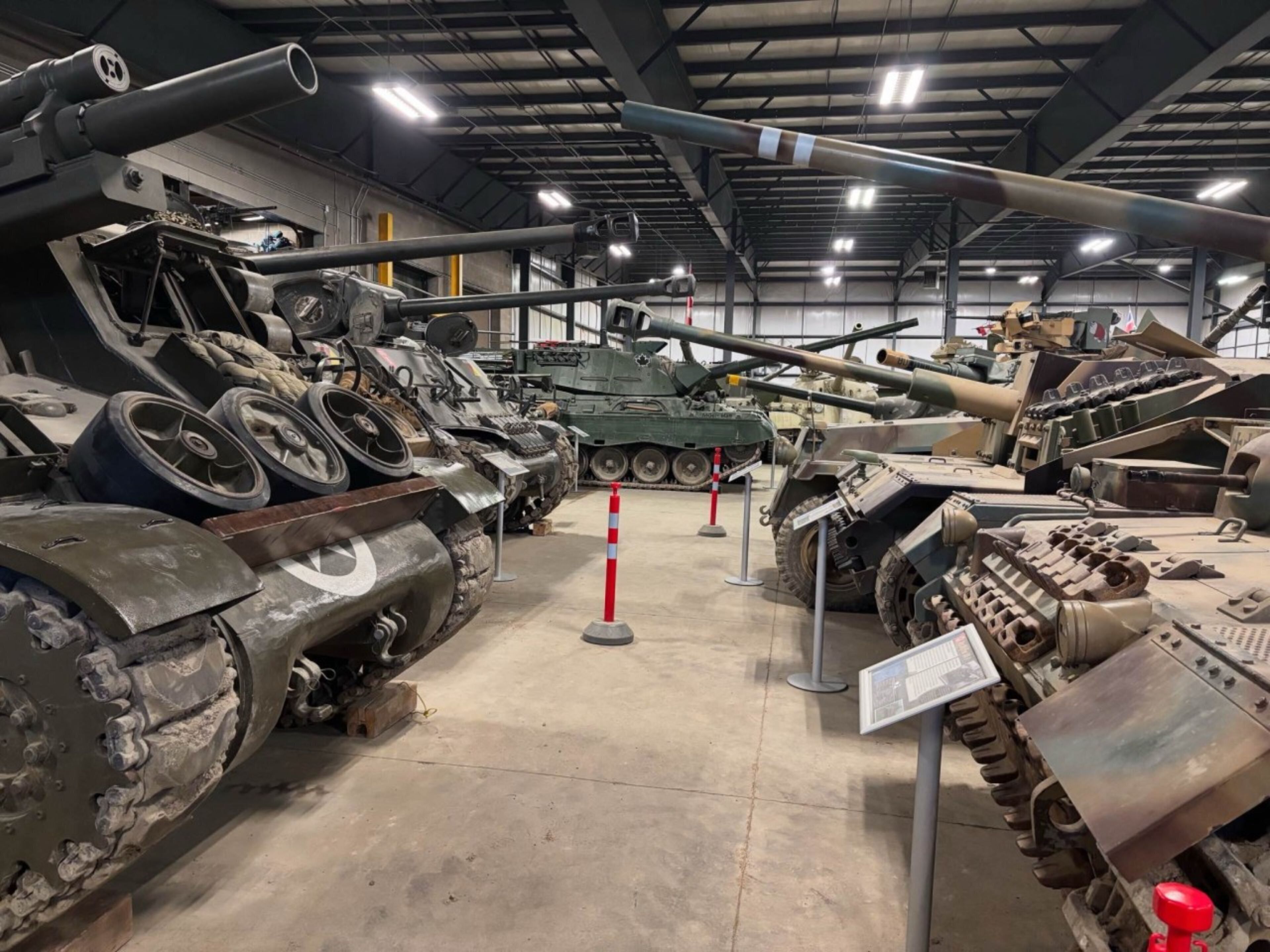 A museum interior with various military tanks on display, including a large cannon and a tank with a turret.