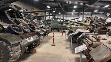 A museum interior with various military tanks on display, including a large cannon and a tank with a turret.