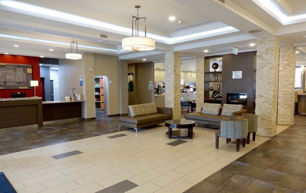 Vestíbulo de hotel con mostrador de recepción, zona de estar y kitchenette.