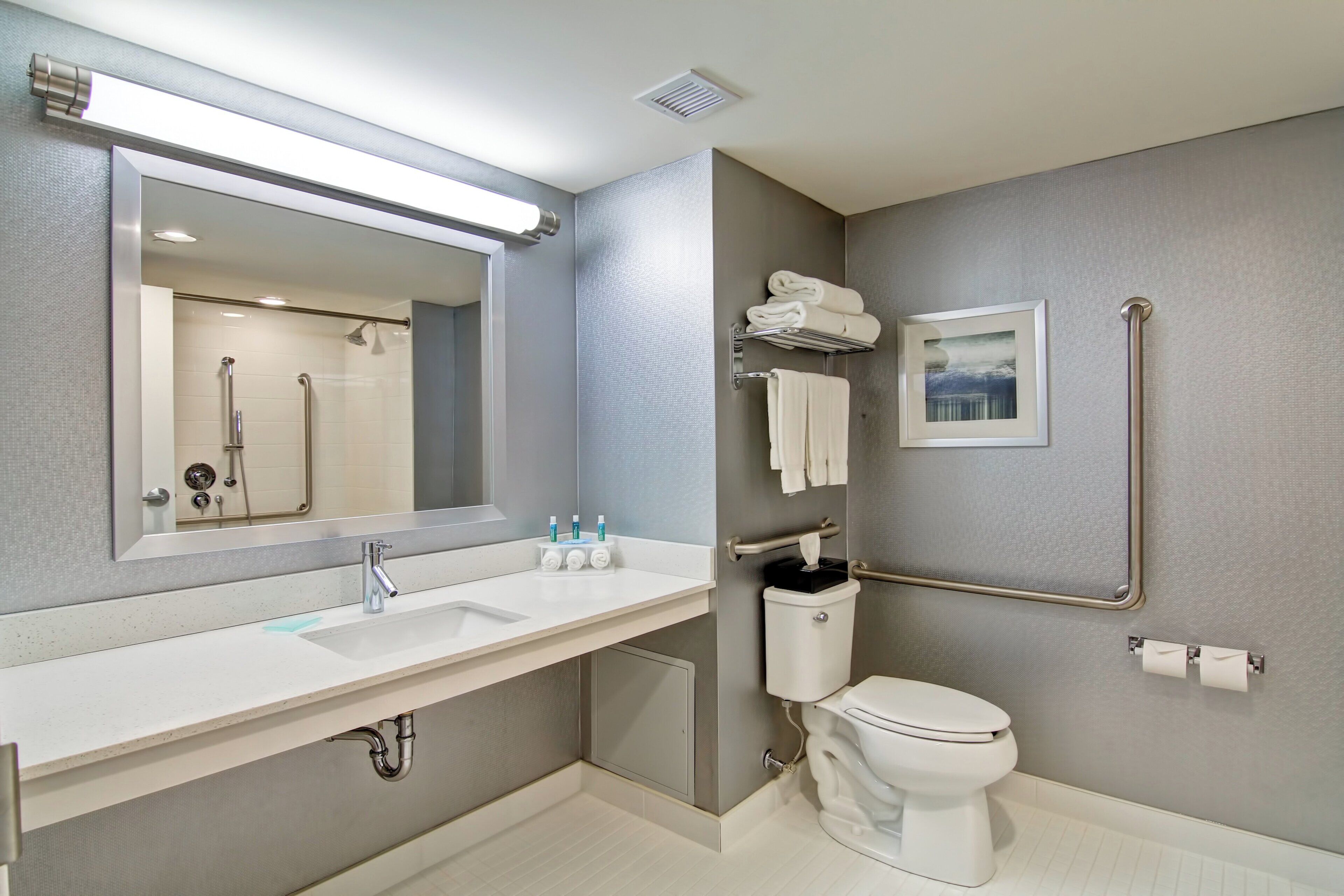 Un baño moderno con un espejo grande, un lavabo, un inodoro y una ducha.