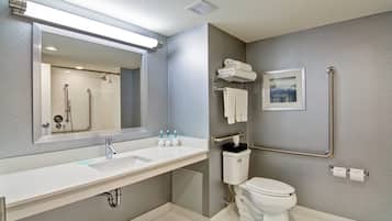 Un baño moderno con un espejo grande, un lavabo, un inodoro y una ducha.