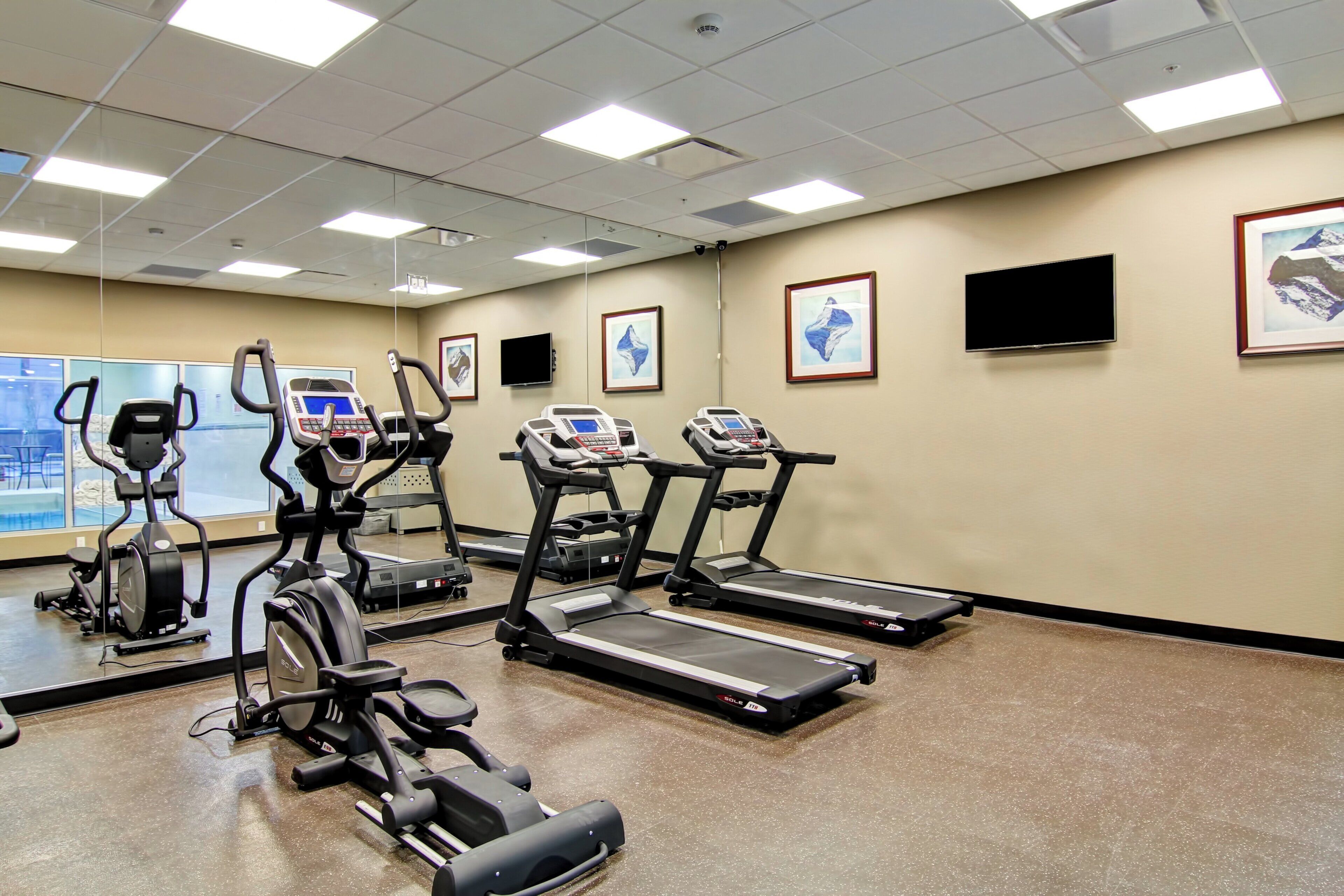 Un gimnasio con cintas de correr, elípticas y bicicletas estáticas.