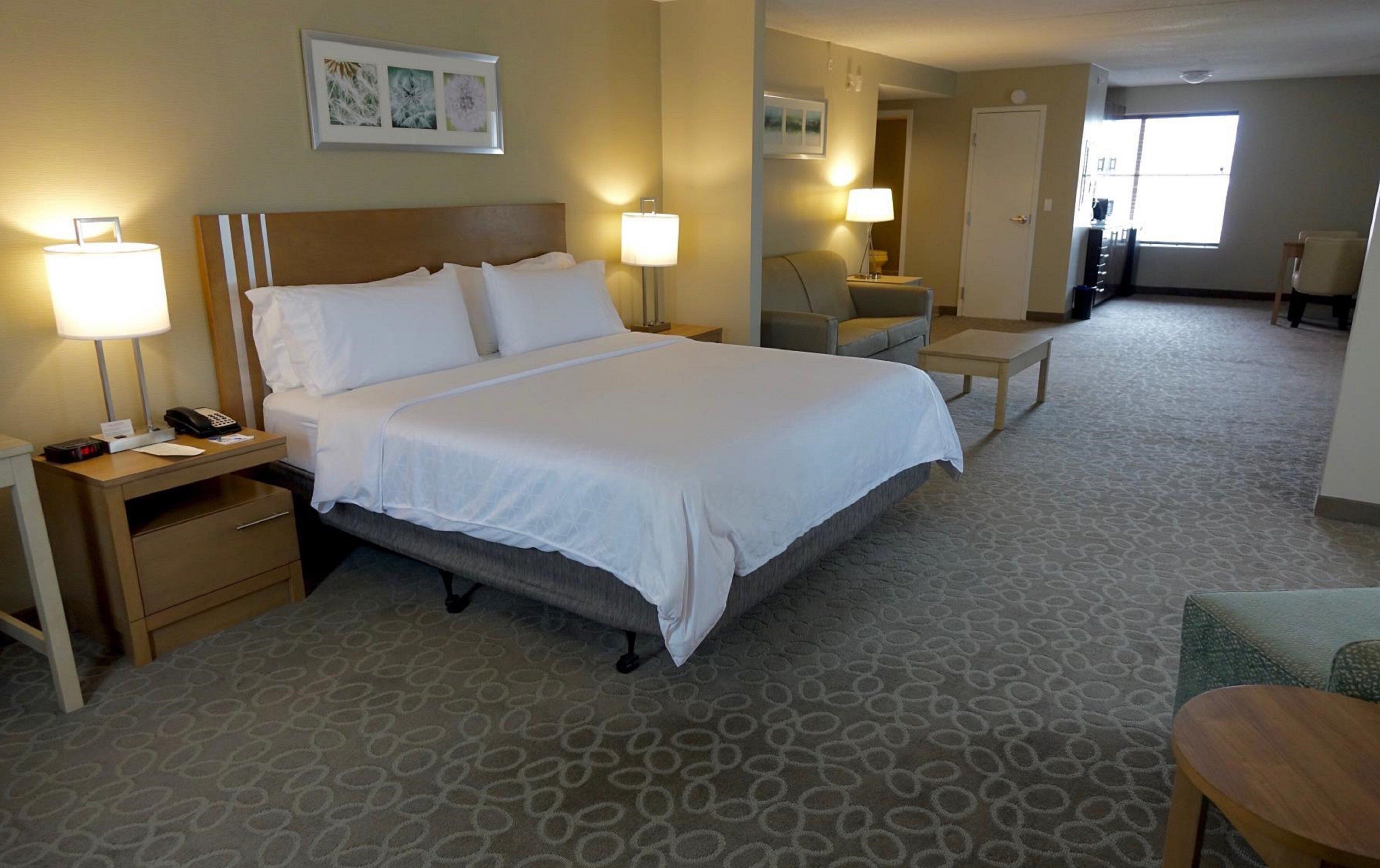 A hotel room with a large bed, bedside lamps, a desk, and a chair.