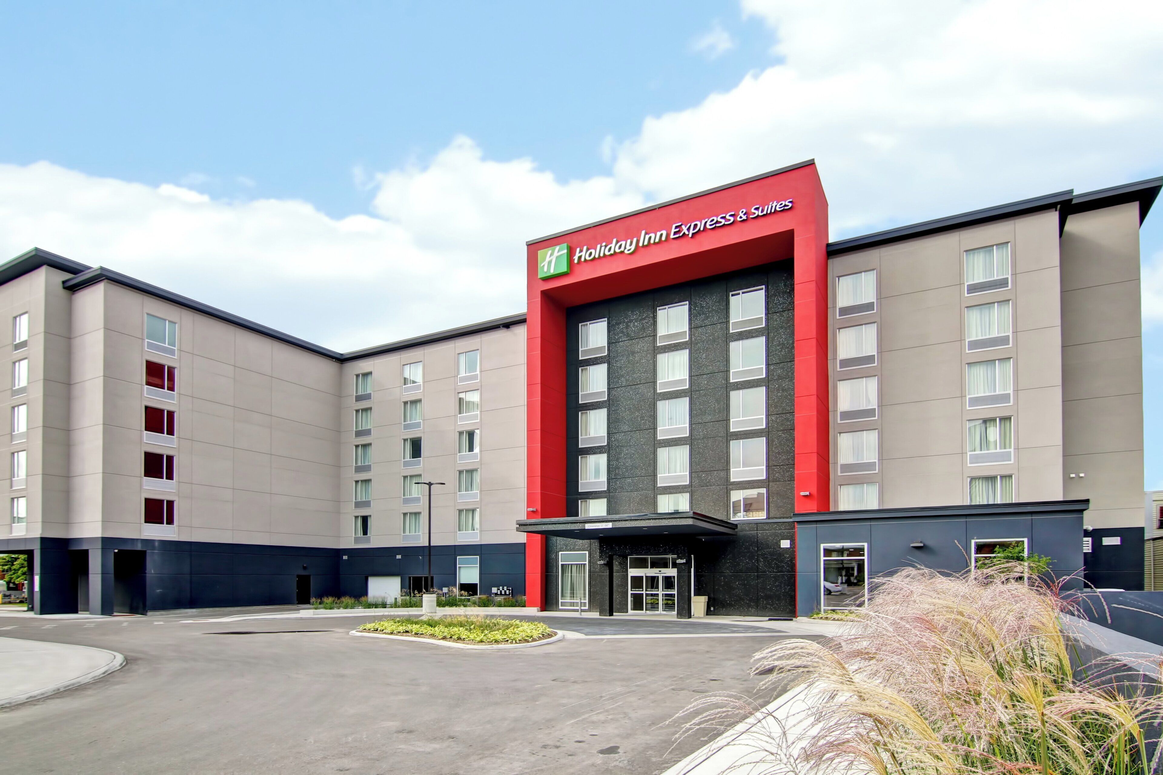 Un hotel Holiday Inn Express & Suites con fachada moderna, varios pisos y una entrada central.