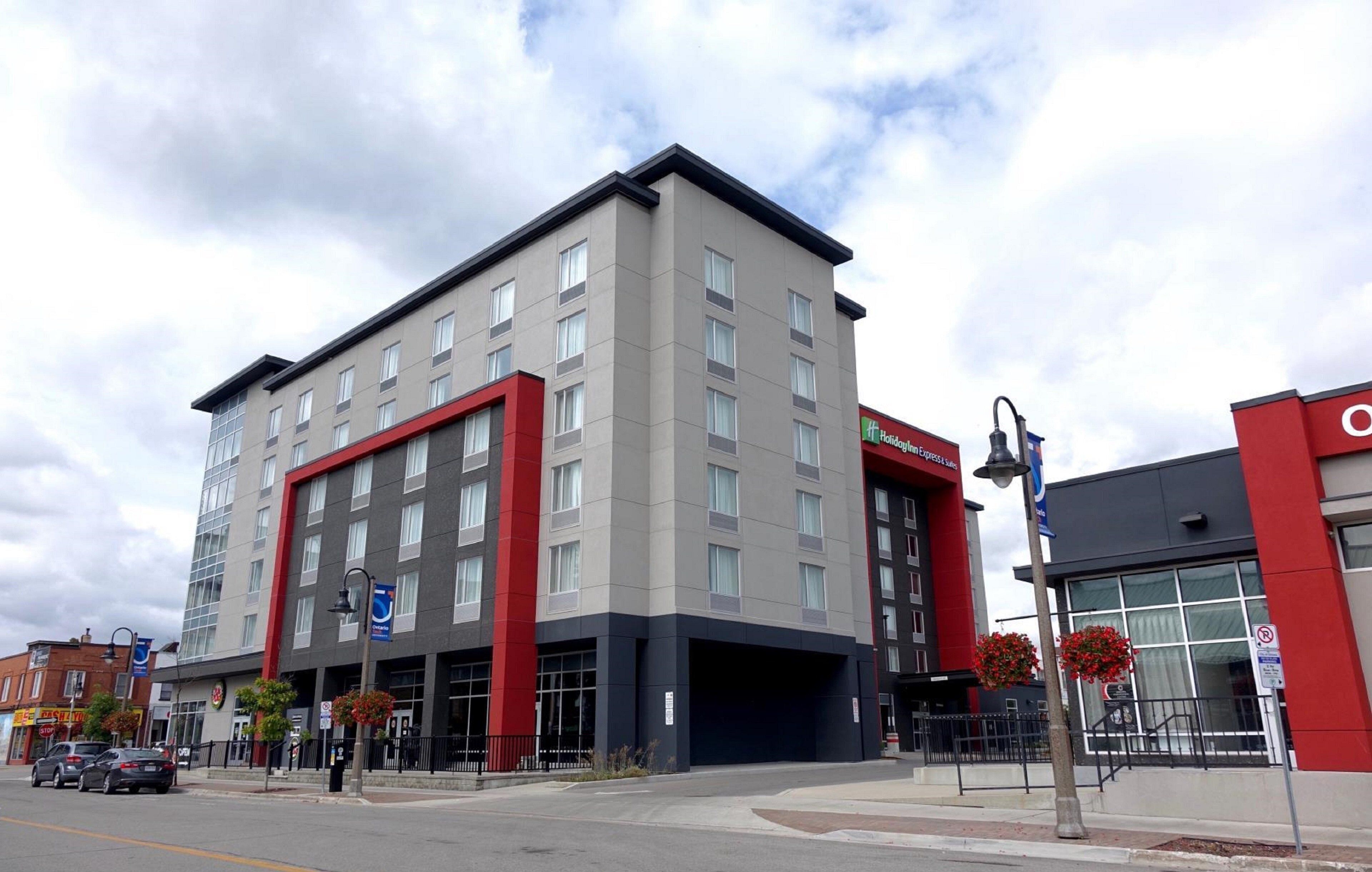 A multi-story hotel with a modern design, featuring a prominent red and grey facade, large windows, and a flat roof.