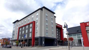 A multi-story hotel with a modern design, featuring a prominent red and grey facade, large windows, and a flat roof.