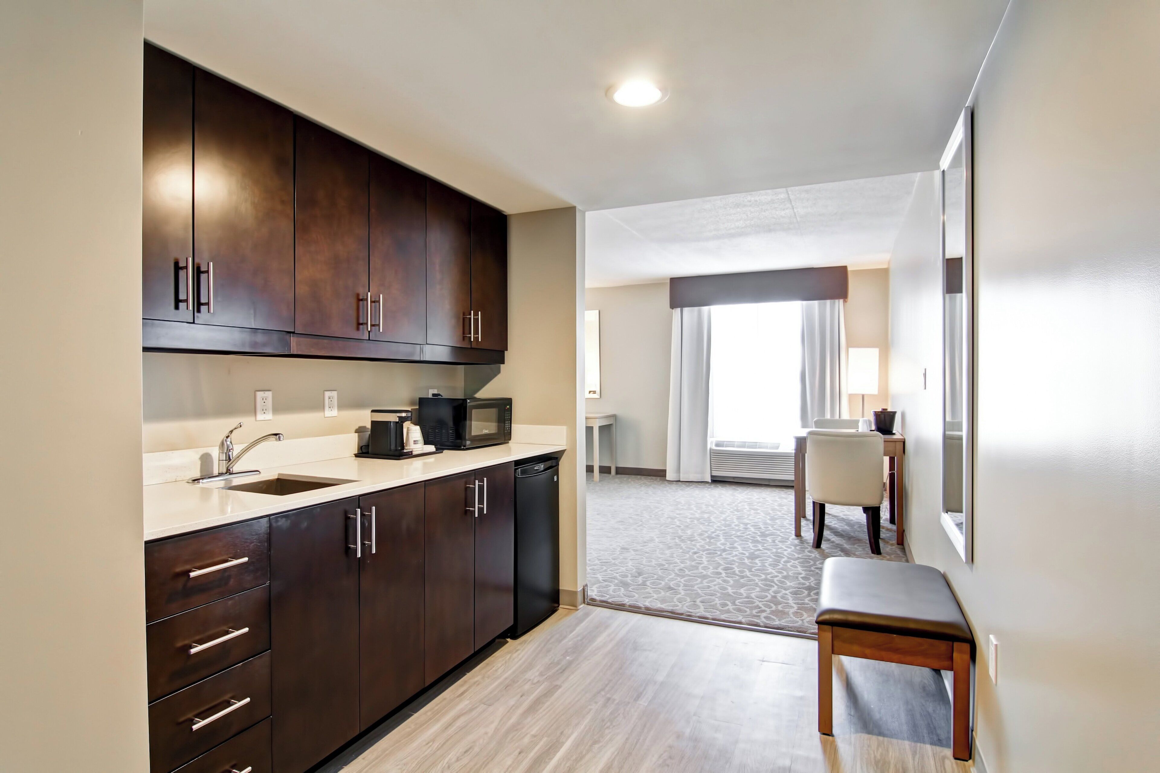 A modern kitchen with dark cabinets, a sink, and a microwave.