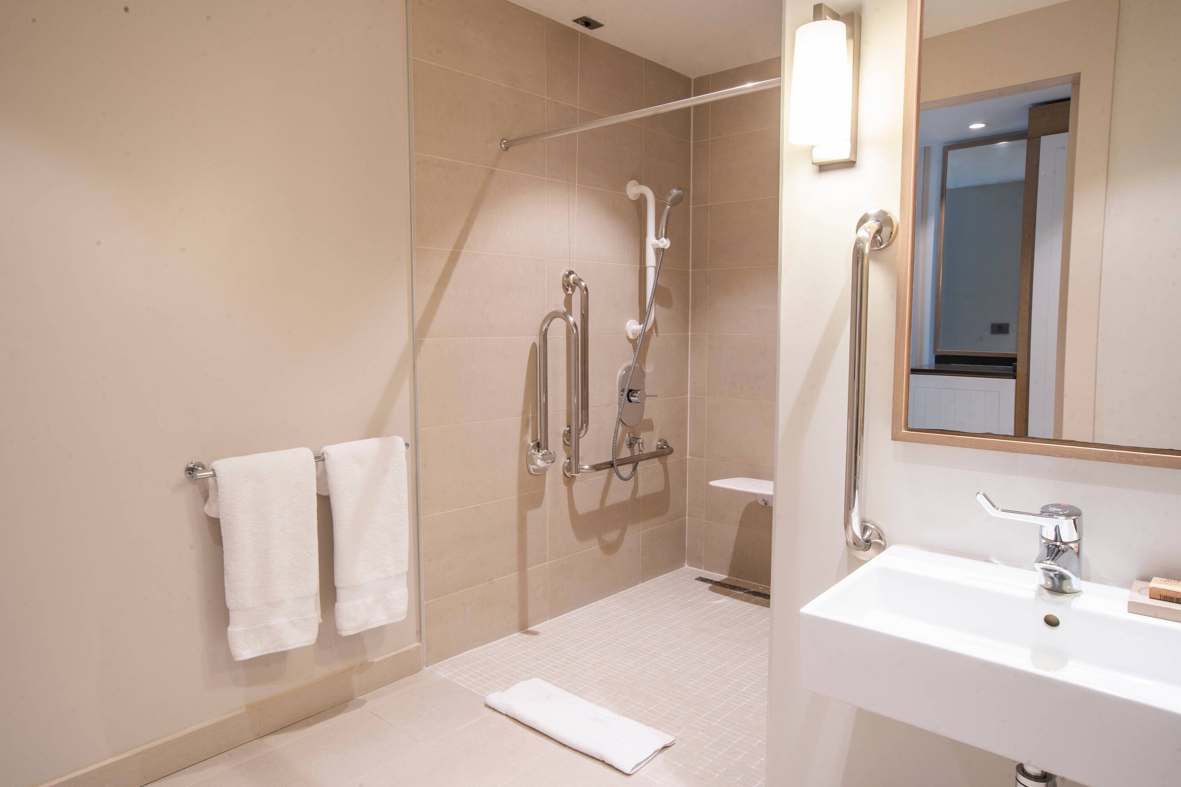 Un bagno moderno con doccia, lavandino e specchio.