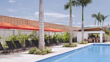 A swimming pool with lounge chairs and palm trees.