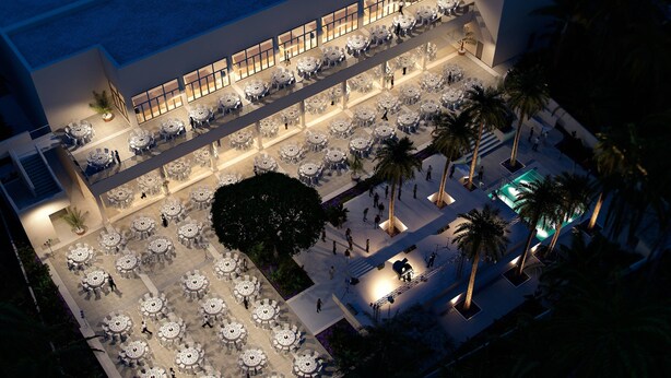 An aerial view of a hotel courtyard with multiple dining areas, palm trees, and a pool.