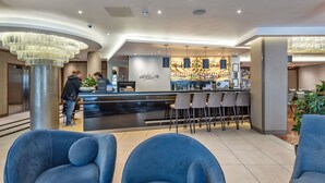 A modern bar area with a counter, bar stools, and a chandelier. - Mercure Edinburgh Haymarket (Edinburgh)