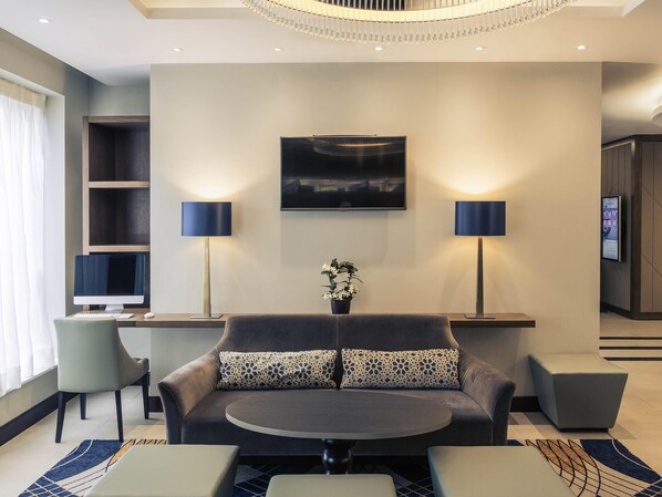 A modern living room with a sofa, two side tables, a flat-screen TV, and a decorative plant. - Mercure Edinburgh Haymarket (Edinburgh)