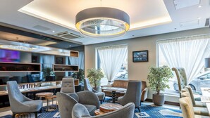 A modern hotel lobby with grey upholstered chairs, a patterned carpet, and a large chandelier. - Mercure Edinburgh Haymarket (Edinburgh)