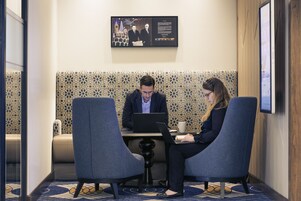 A meeting room with two people at a table, one using a laptop.
