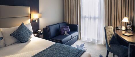 Een hotelkamer met een bed, een bank, een bureau en een stoel.