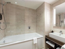 Une salle de bain moderne équipée d’une baignoire, d’une douche, d’un lavabo et d’un miroir.