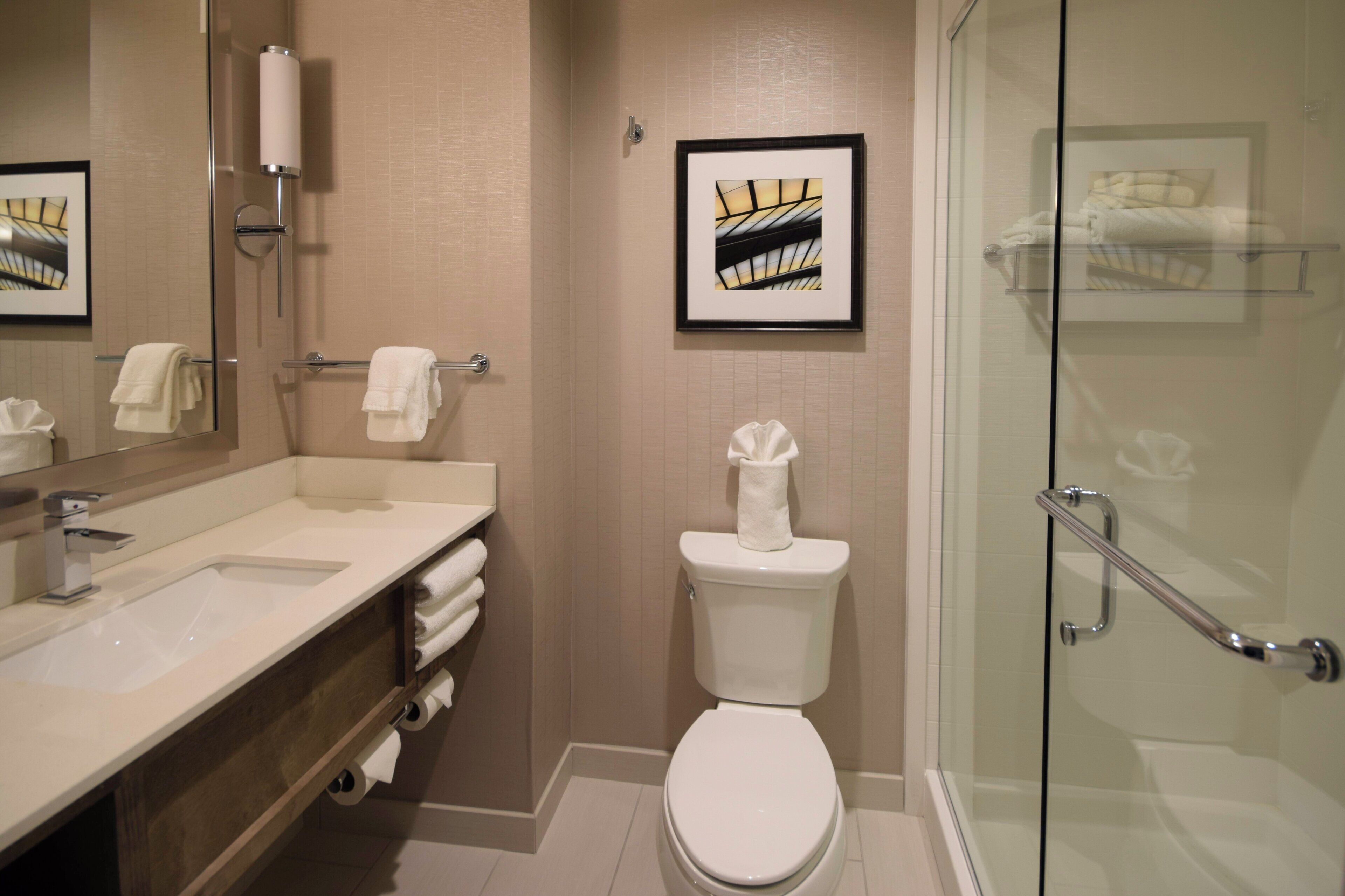 Une salle de bain moderne avec une douche à parois de verre, des toilettes blanches et un meuble-lavabo avec un miroir et un évier.
