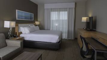 Habitación de hotel con cama, mesitas de noche, escritorio, silla y televisión.