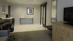 A modern office space with a desk, chair, computer, and television. - Holiday Inn Cincinnati N - West Chester by IHG (West Chester)