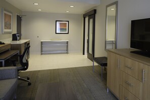 A modern office space with a desk, chair, computer, and television. - Holiday Inn Cincinnati N - West Chester by IHG (West Chester)