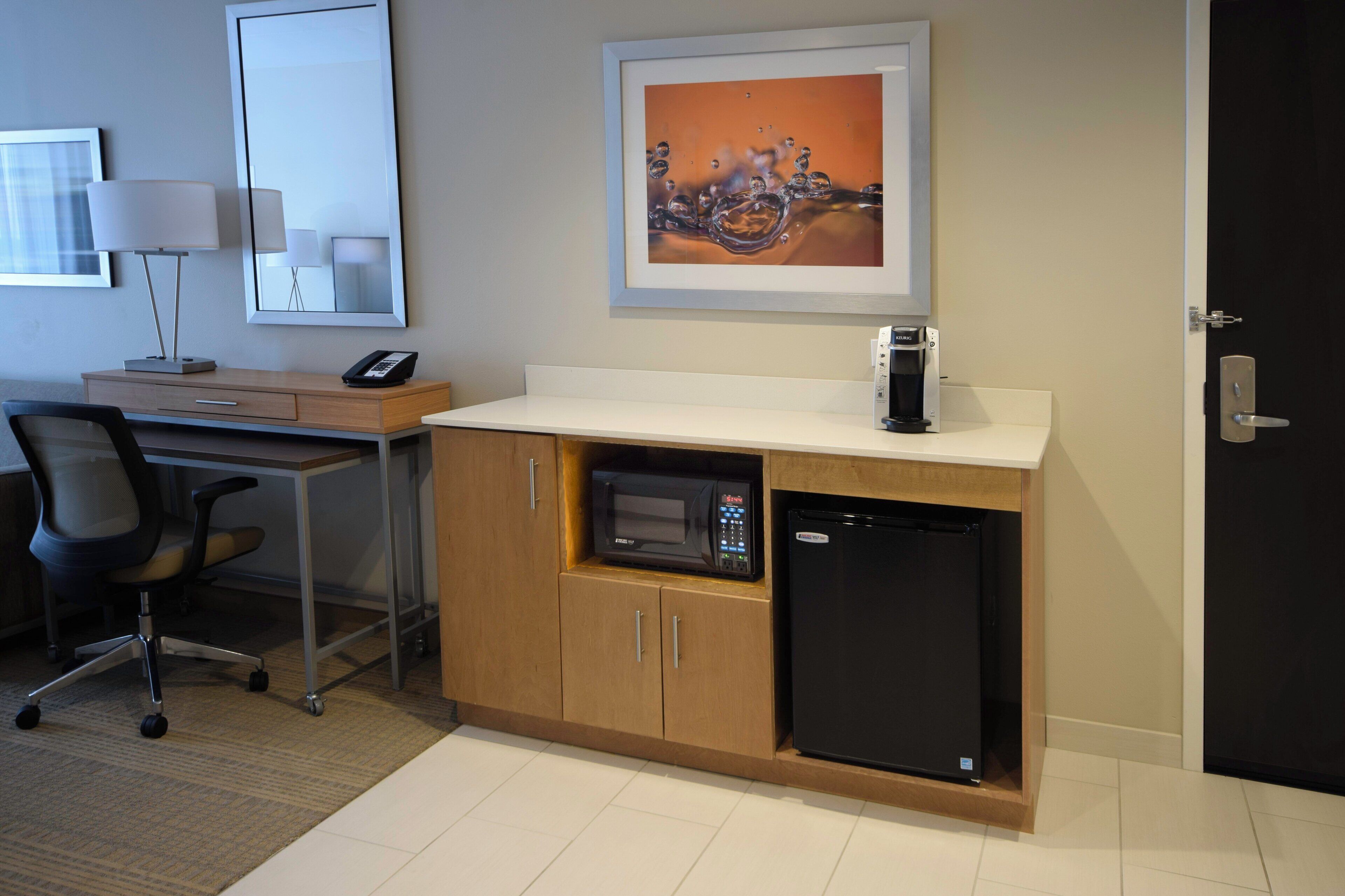 A kitchenette with a microwave, refrigerator, and coffee maker.