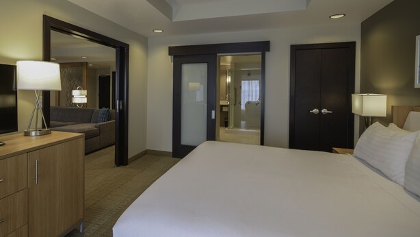 A hotel room with a large bed, a desk with a lamp, a wardrobe, and a mirror. - Holiday Inn Cincinnati N - West Chester by IHG (West Chester)