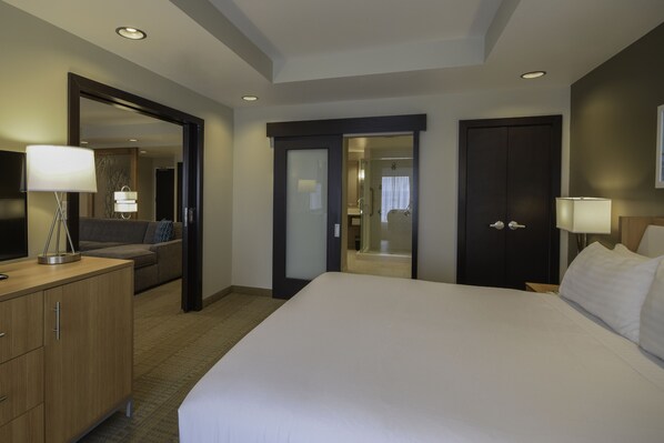 A hotel room with a large bed, a desk with a lamp, a wardrobe, and a mirror. - Holiday Inn Cincinnati N - West Chester by IHG (West Chester)