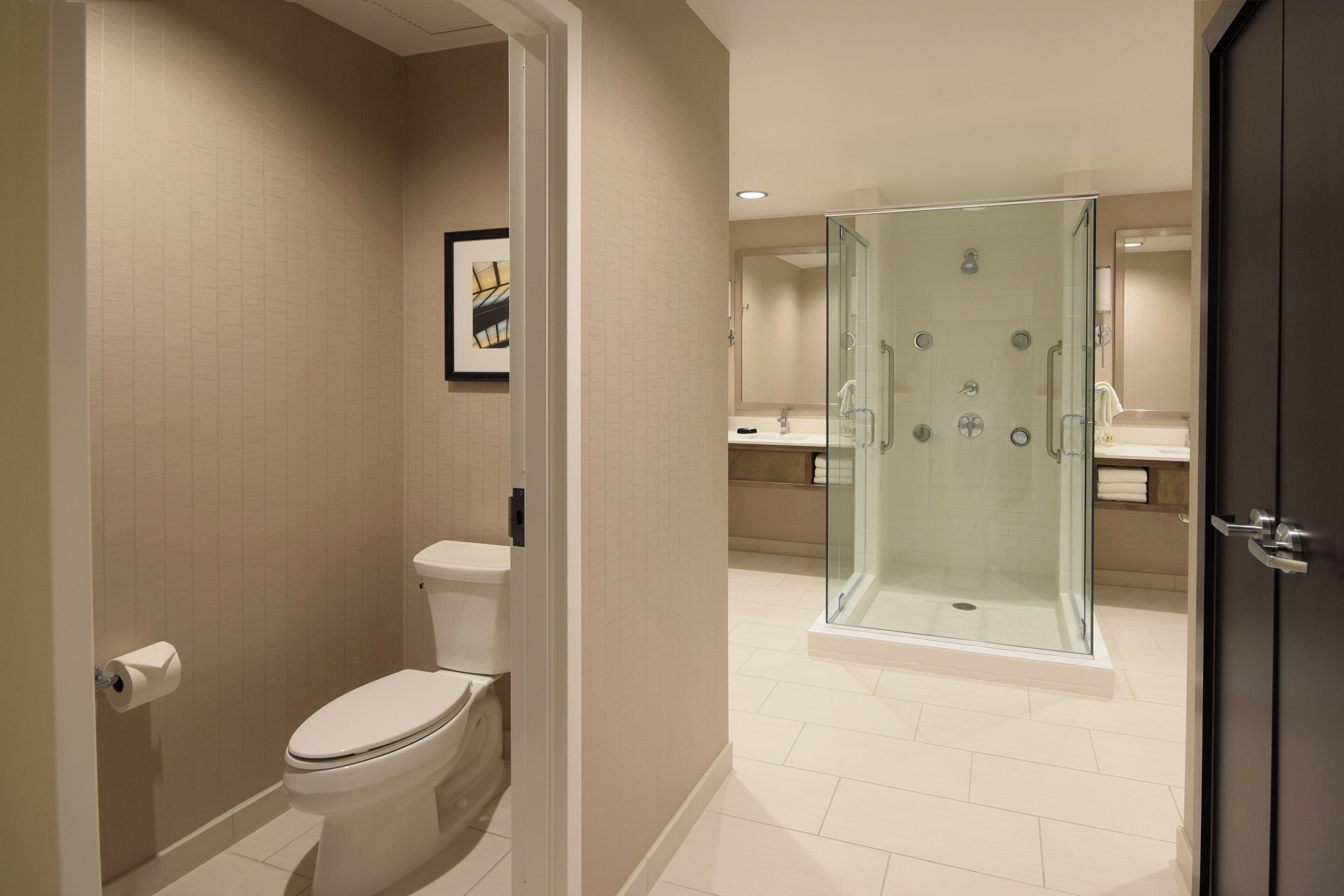 Un baño moderno con inodoro, ducha envuelta en vidrio y lavamanos.