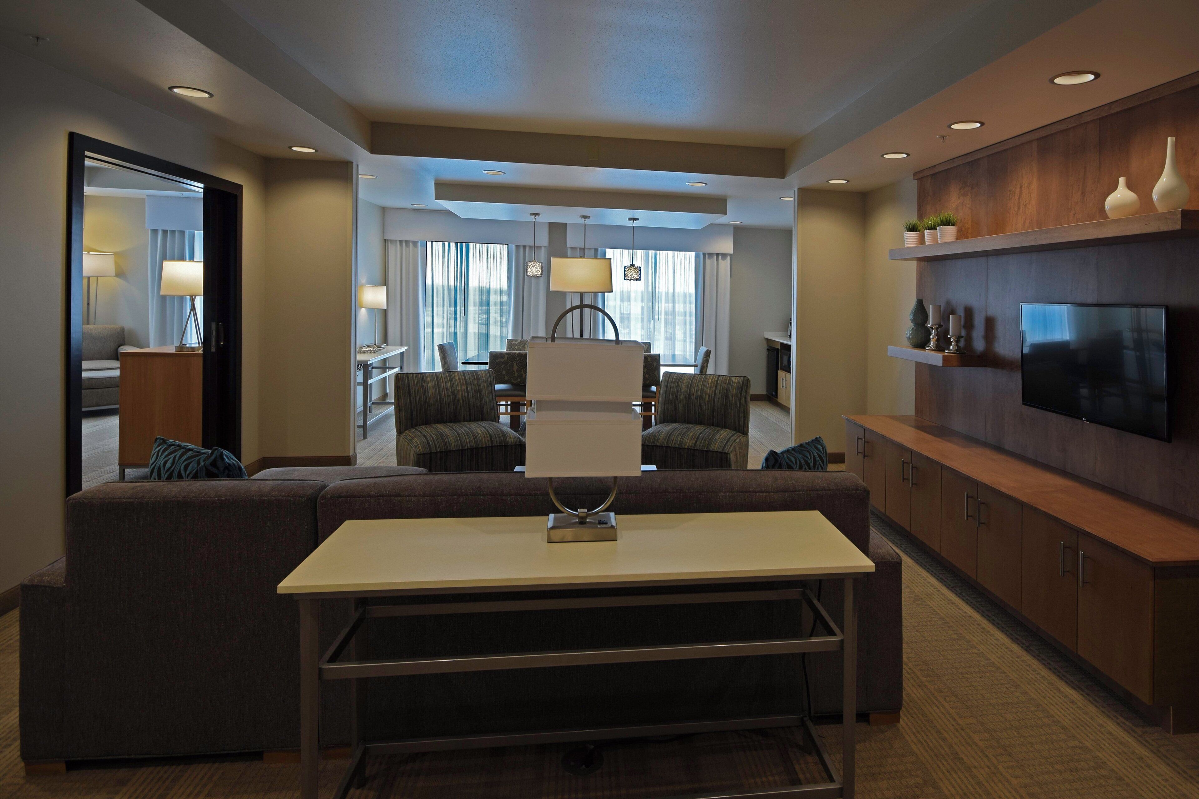 Una habitación de hotel moderna con sofá, mesa de comedor y televisión.