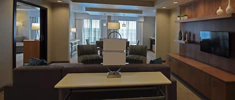 Una habitación de hotel moderna con sofá, mesa de comedor y televisión.