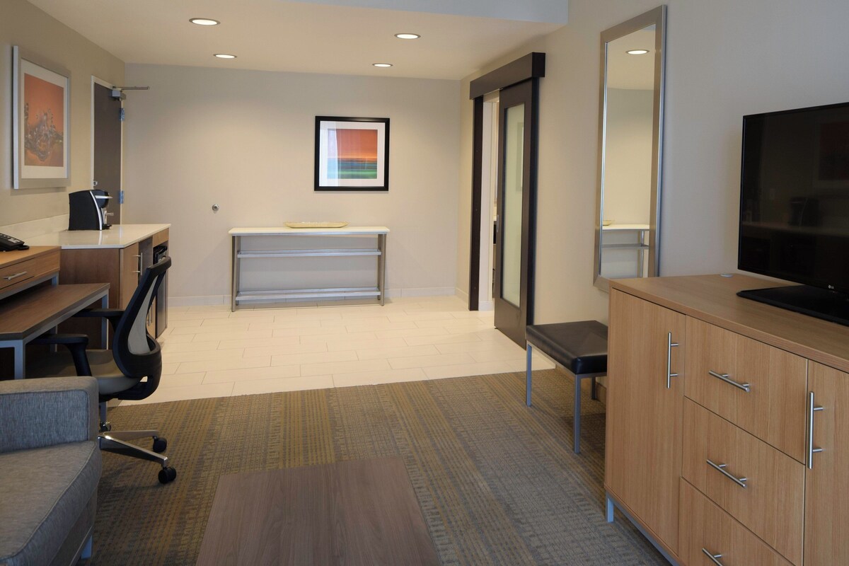 A modern office space with a desk, office chair, television, and cabinets.