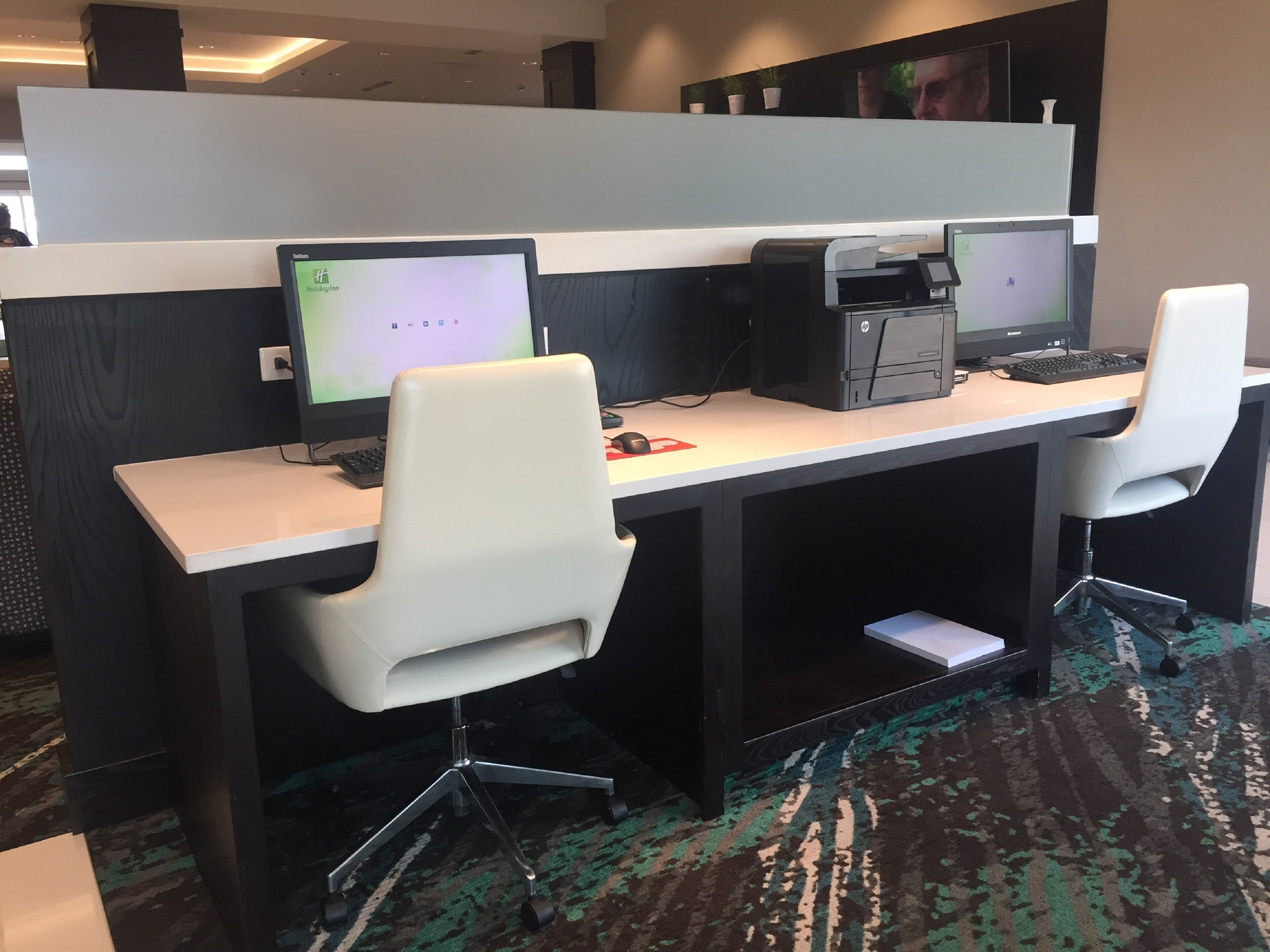 A modern office space with two desks, each with a computer and a chair.