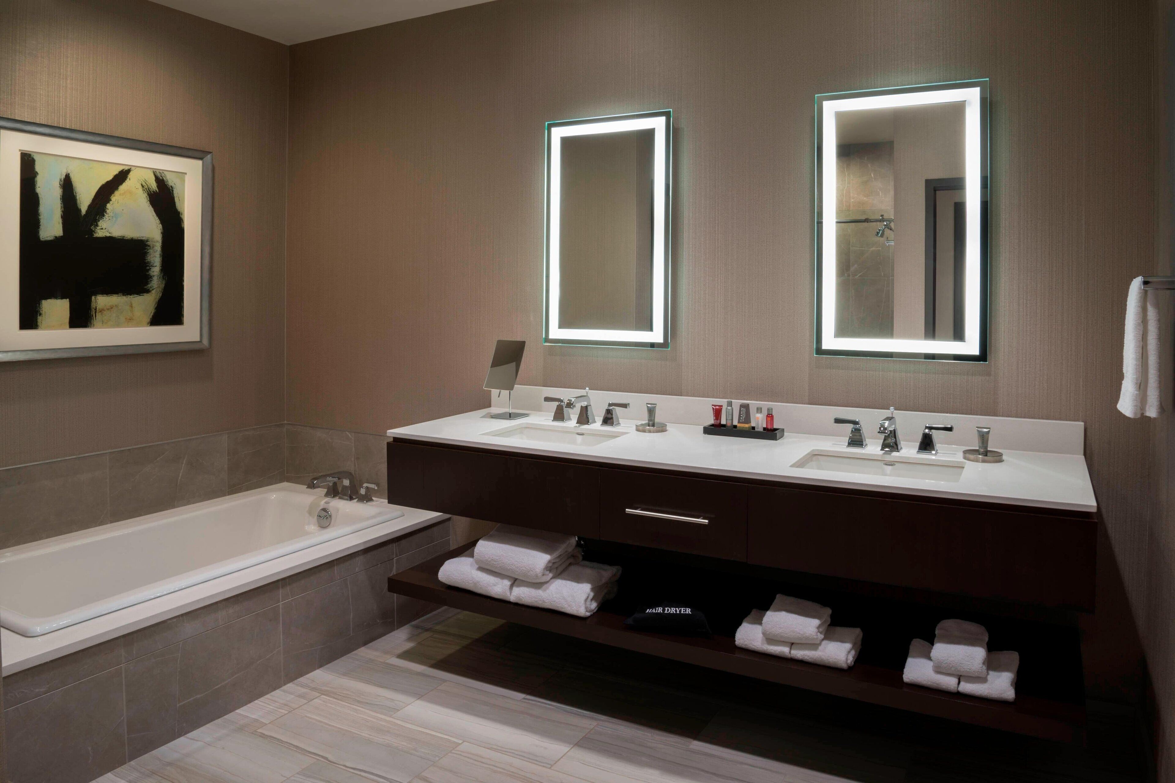 A modern bathroom with a double sink vanity, a large mirror, and a built-in towel rack.