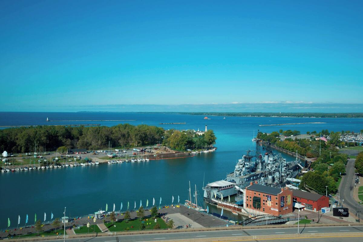 A marina with boats, a large ship, and a red building with a sign.
