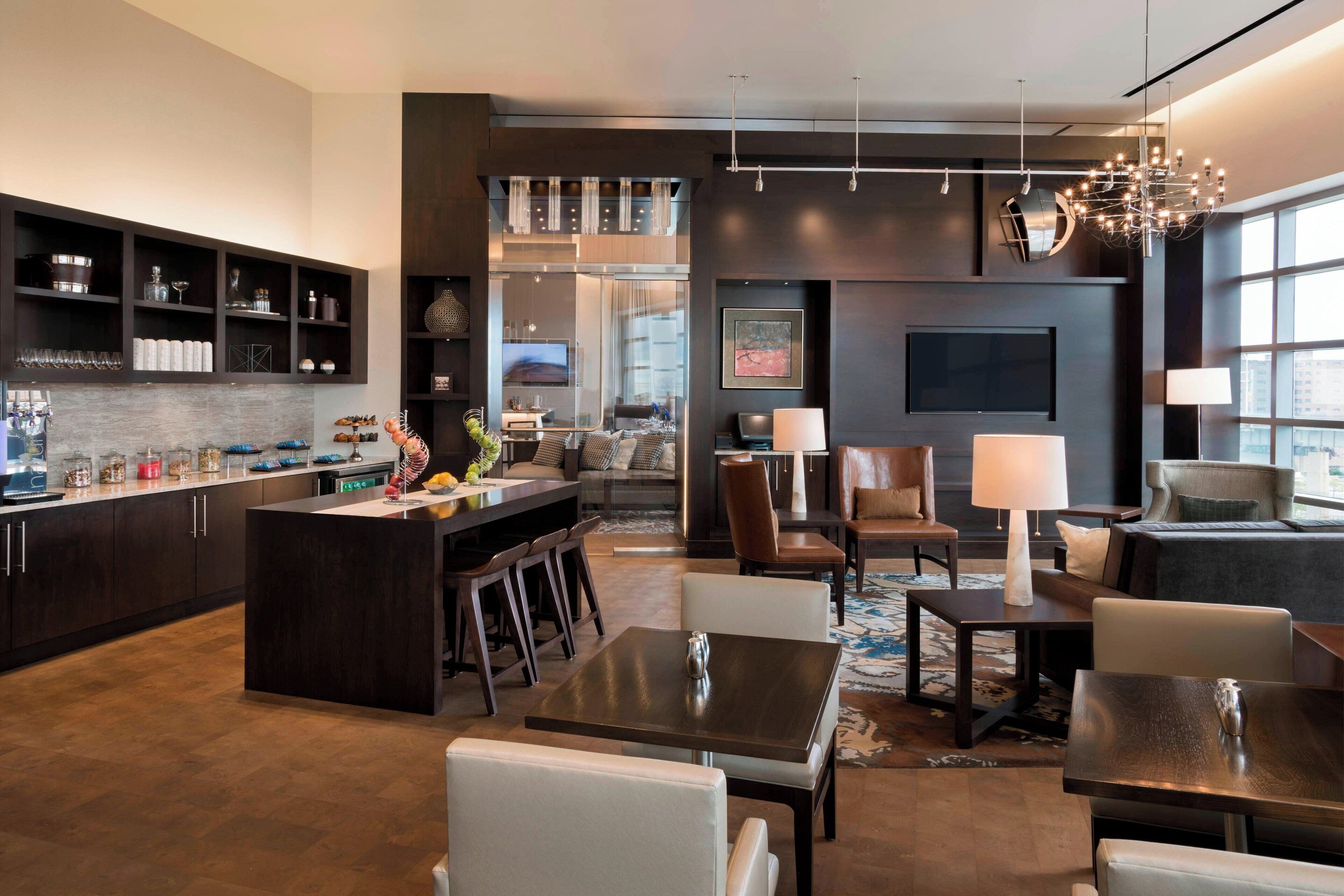 A modern hotel lobby with a central island, seating areas, and a large window providing a view.