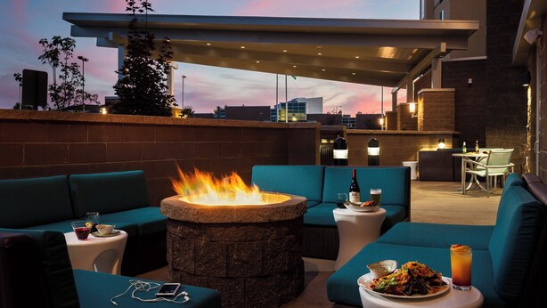 An outdoor seating area with a fire pit, blue sofas, and a table with drinks. - SpringHill Suites by Marriott Kennewick Tri-Cities (Kennewick)
