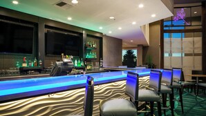 A bar area with a long counter, bar stools, and a variety of bottles. - SpringHill Suites by Marriott Kennewick Tri-Cities (Kennewick)
