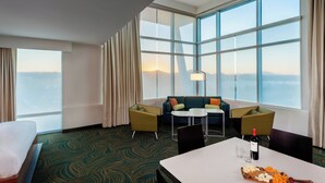 A hotel room with a large window, a bed, a dining table with a wine bottle, and a sofa set. - SpringHill Suites by Marriott Kennewick Tri-Cities (Kennewick)