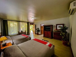 A hotel room with two beds, a TV, a desk, and a dining area.