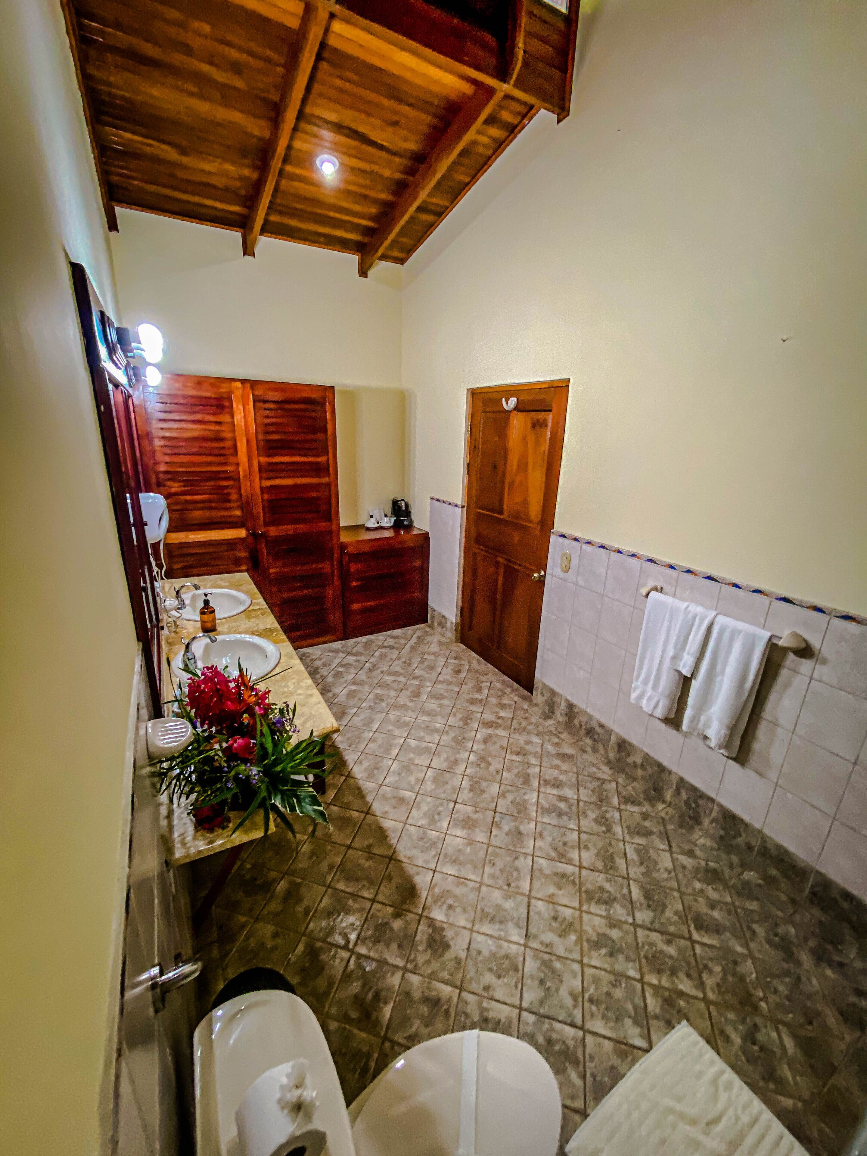 Une salle de bain avec un plafond en bois, un lavabo, des toilettes et un espace douche.