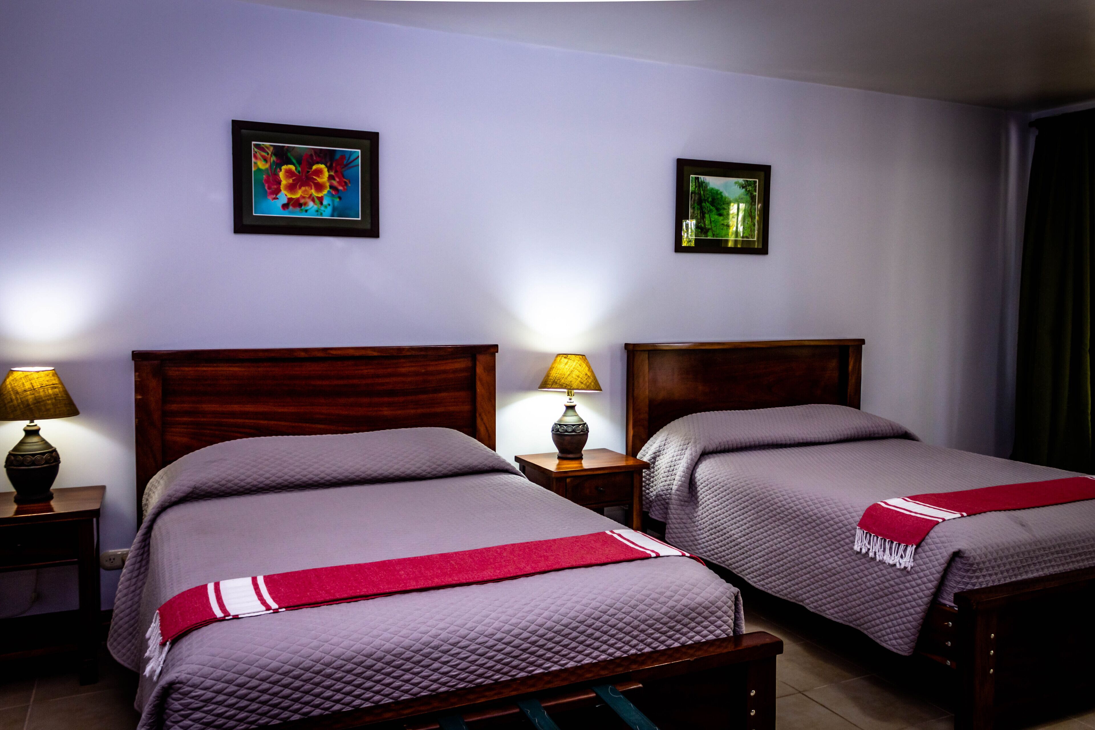 A hotel room with two beds, wooden headboards, and bedside tables with lamps.