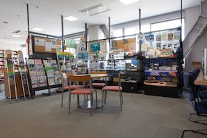 A bookstore with bookshelves, tables, chairs, and a staircase. - Shin-Osaka Youth Hostel (Osaka)