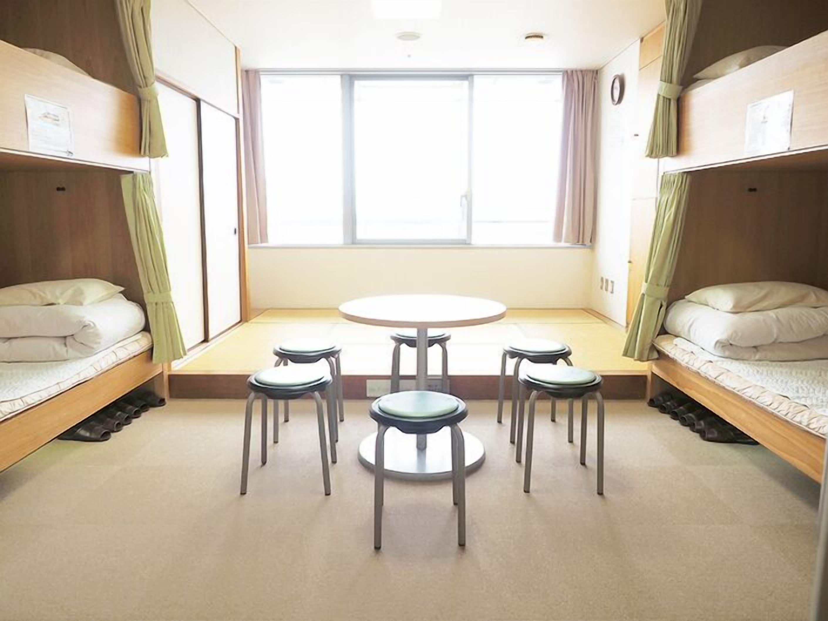 Um quarto de dormitório com beliches, uma mesa redonda e quatro cadeiras.