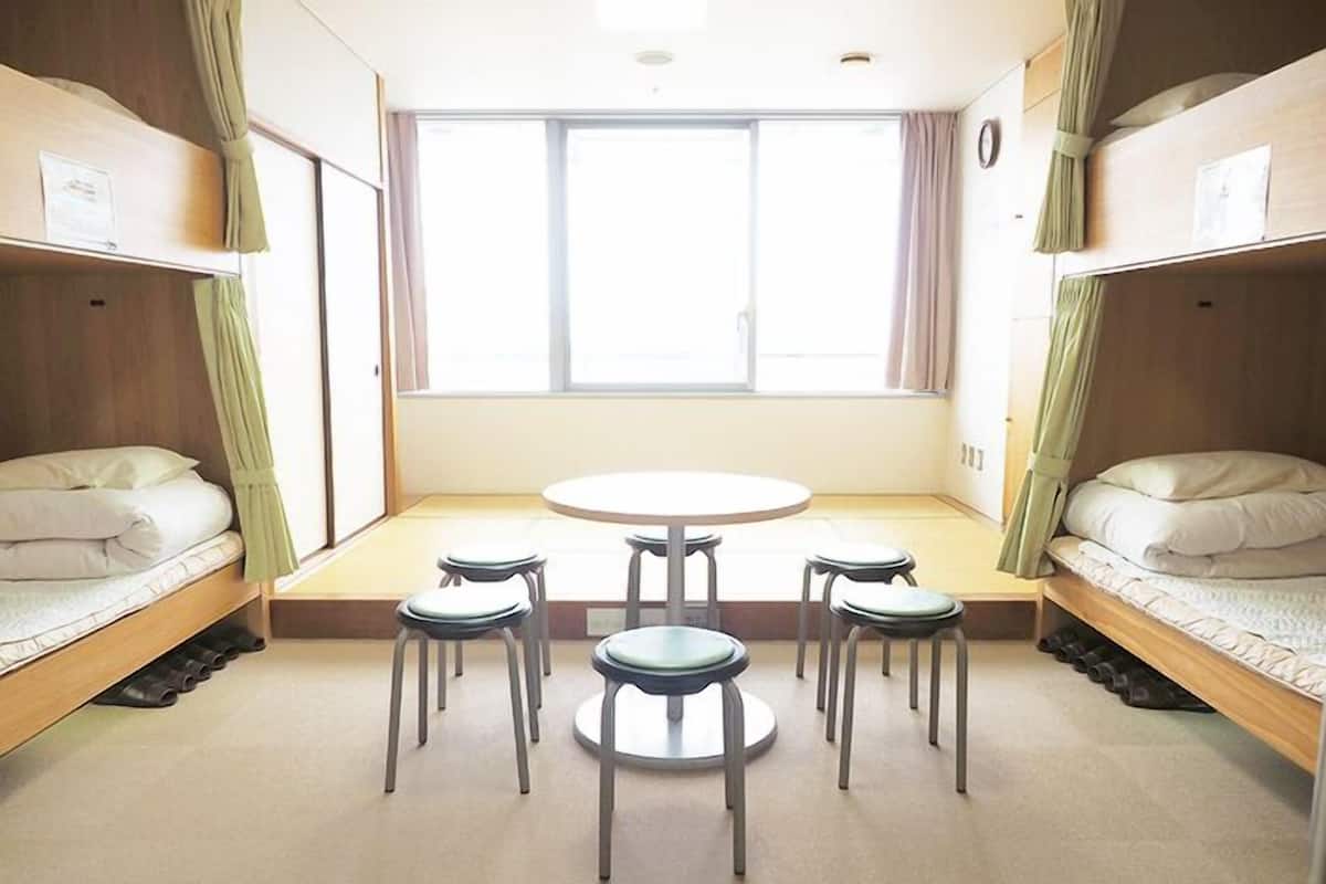 Une chambre de dortoir avec des lits superposés, une table ronde et quatre chaises.