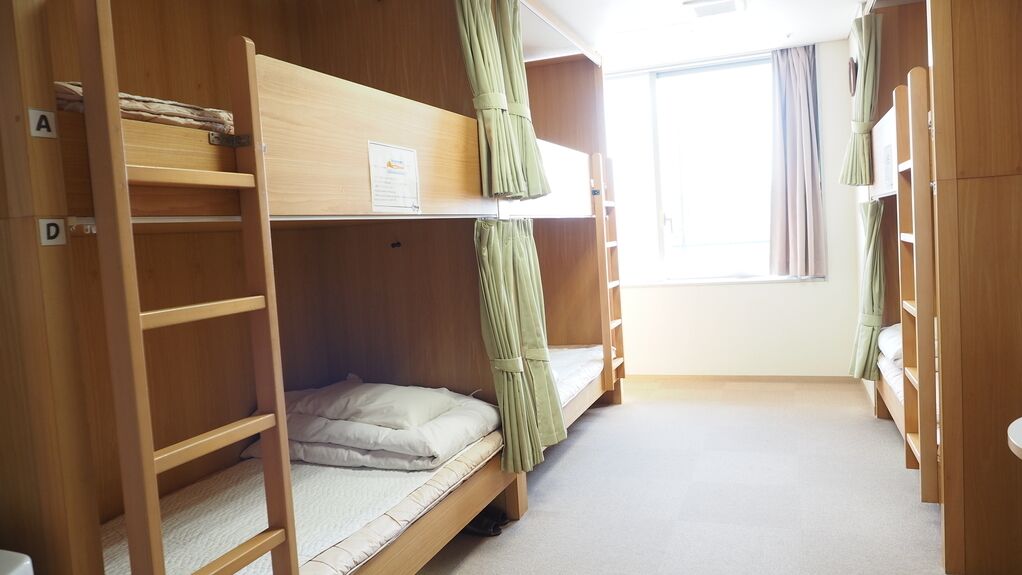 Quarto com beliche, janela, cortinas e guarda-roupa de madeira.