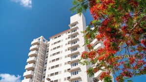 Un immeuble de grande hauteur doté de nombreux balcons, avec un ciel bleu dégagé.