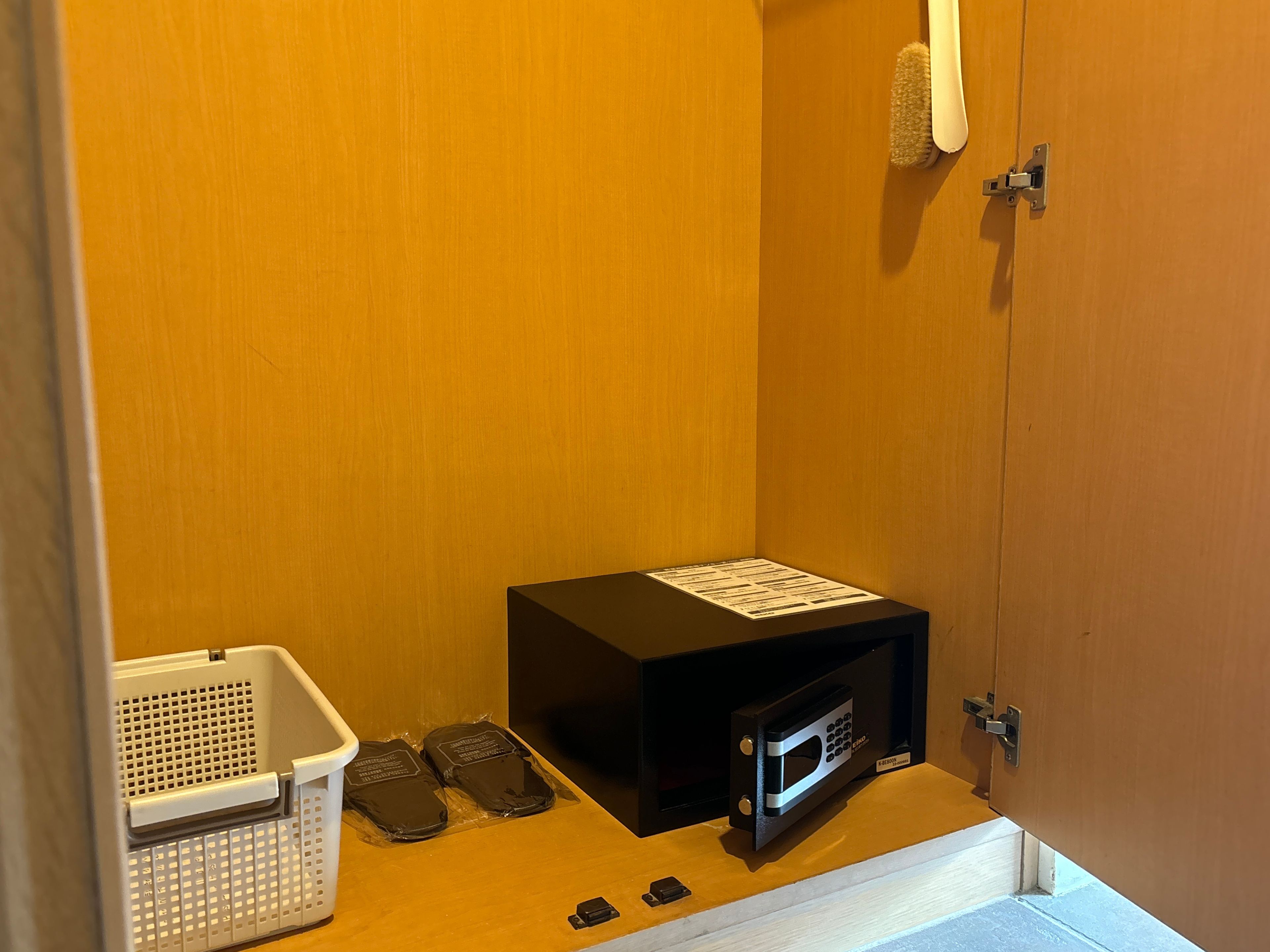 Un petit espace clos comprenant un four à micro-ondes, un panier et une paire de chaussons.