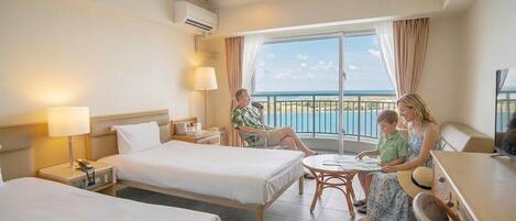 Habitación de hotel con dos camas, un balcón con vistas y un comedor.