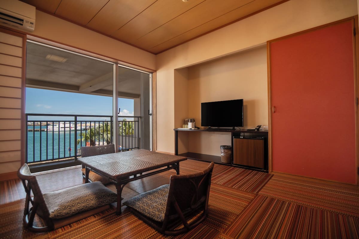 Een balkon met uitzicht op zee, een flatscreen televisie en een klein tafeltje met stoelen.