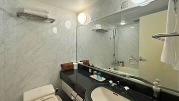A modern bathroom with a marble wall, a black sink, a toilet, and a large mirror.